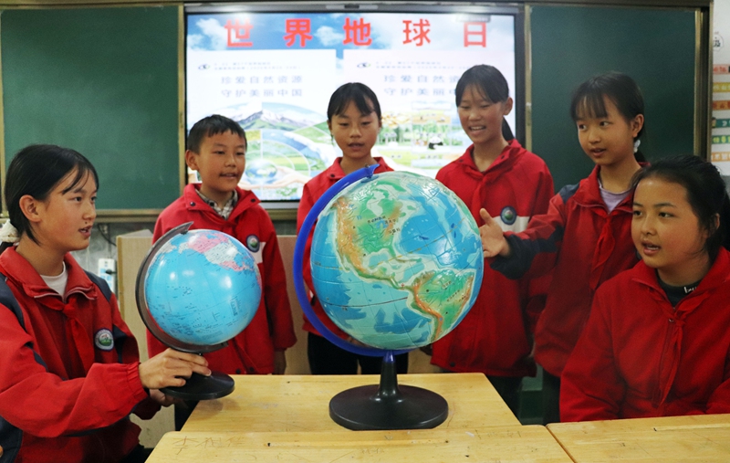 小学生正通过地球仪学习地球科学知识。