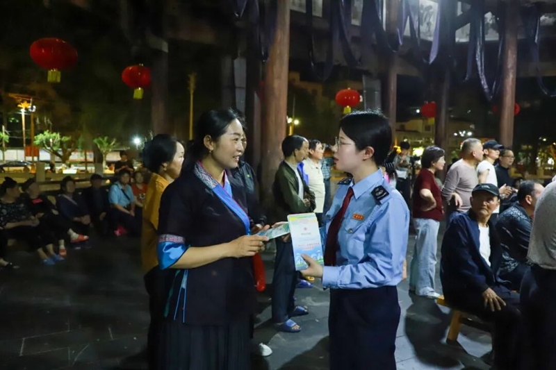 图为税务干部向现场少数民族群众开展税费知识宣传