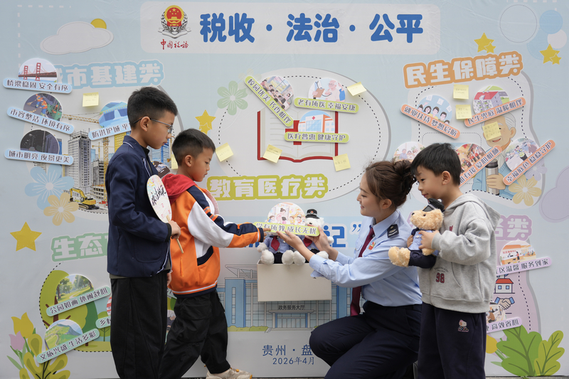 税务干部协助青少年儿童粘贴主题贴纸.