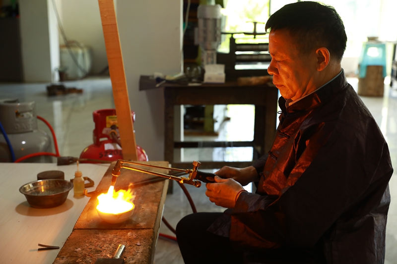 剑河县银匠邰引岩在制作银饰。