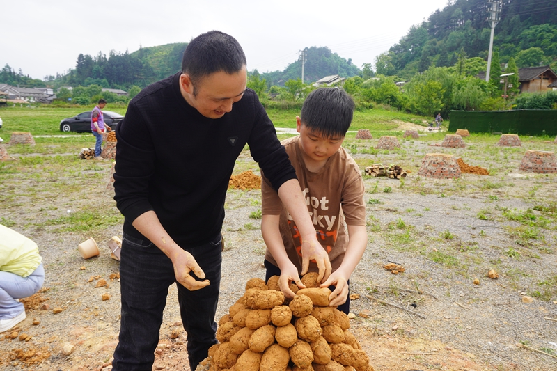 游客和孩子一起协作垒窑。