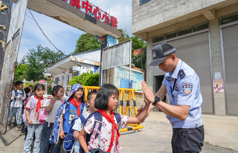2026年6月4日，贵州省毕节市纳雍县乐治镇中心学校，执勤民警在和学生击掌约定路上注意安全。 杨英 摄.jpg