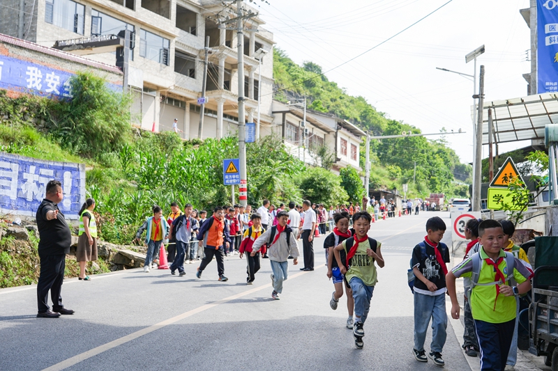 2026年6月4日，贵州省毕节市纳雍县乐治镇中心学校，学生在护学人员引导下安全过马路。 杨英 摄.jpg