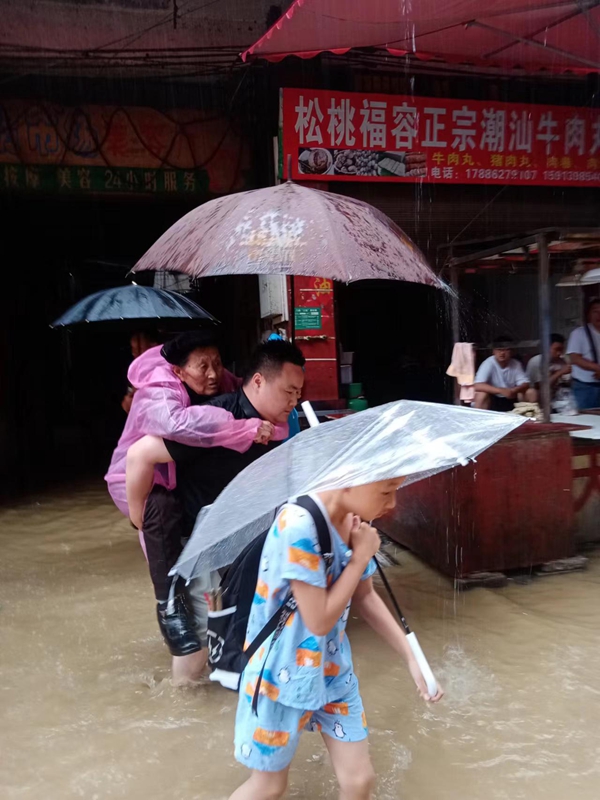 6月7日上午，松桃遭强降雨袭击，黔东农贸市场低洼部分区域发生严重内涝，街道领导冒雨背驮行动不便独居老人转移安全区域.jpg