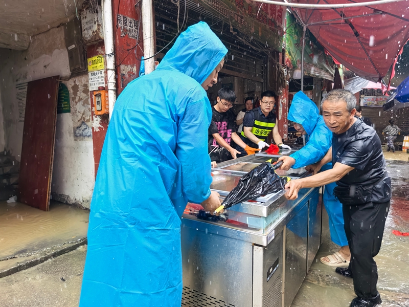 6月7日上午，松桃遭强降雨袭击，黔东农贸市场低洼部分区域发生严重内涝，党工委领导冒雨帮商户物资.jpg