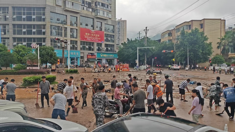 党员干部群众在县一小路段清理淤泥和积水。