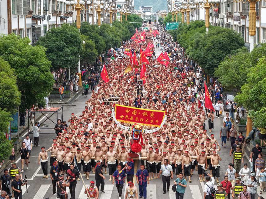 人們抬著獨木龍舟進行巡游活動。