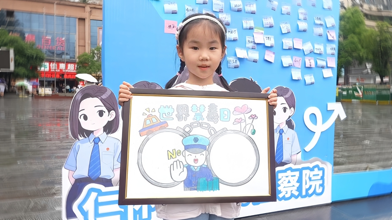 禁毒游园会现场，小朋友展示自己的禁毒画作。.jpg