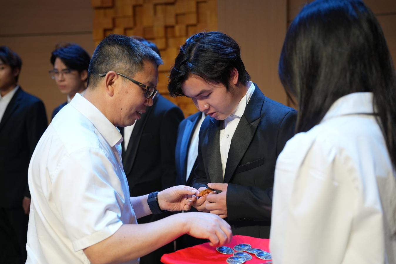 图三为李泽平副校长为新入团成员授胸牌。