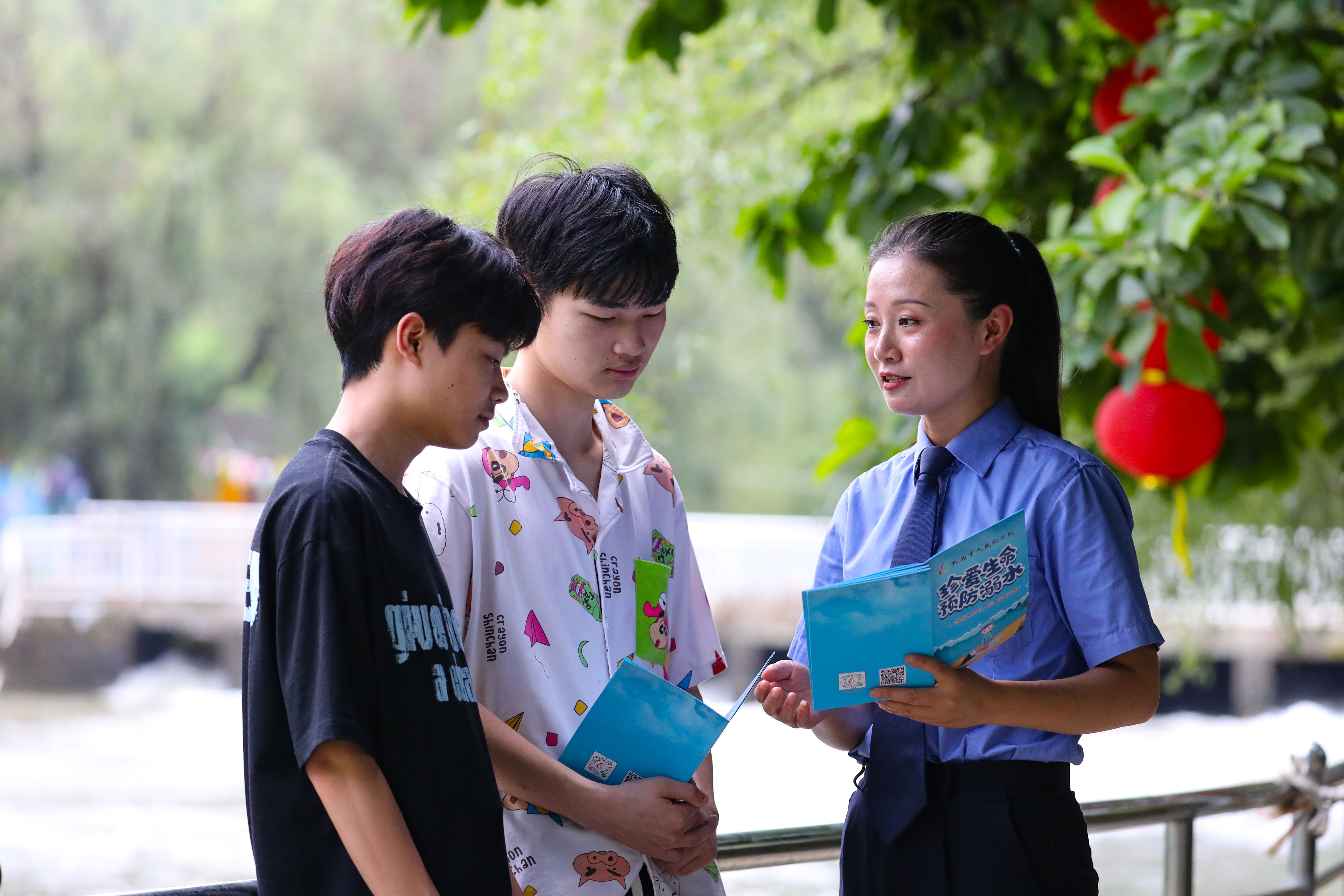 2026年7月7日中午，黔西市检察院检察干警走进洪水镇解放村柳岸水乡景区，开展防溺水法治安全教育活动。图为检察干警正在给游玩的青少年讲解防溺水知识。