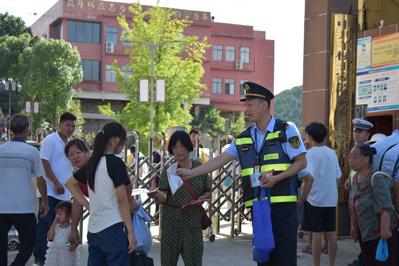 2 执法人员在学校门口发放宣传单,叮嘱学生禁止乘坐“黑车”