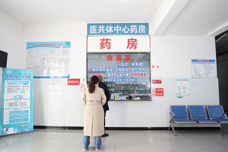 三都县大河镇居民在卫生院药房取药。