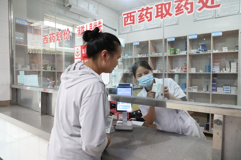 三都县都江镇居民在卫生院药房取药。