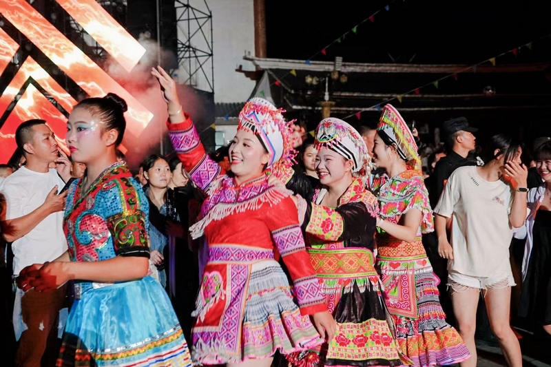 苗族同胞们正和大家一起围着篝火跳舞。