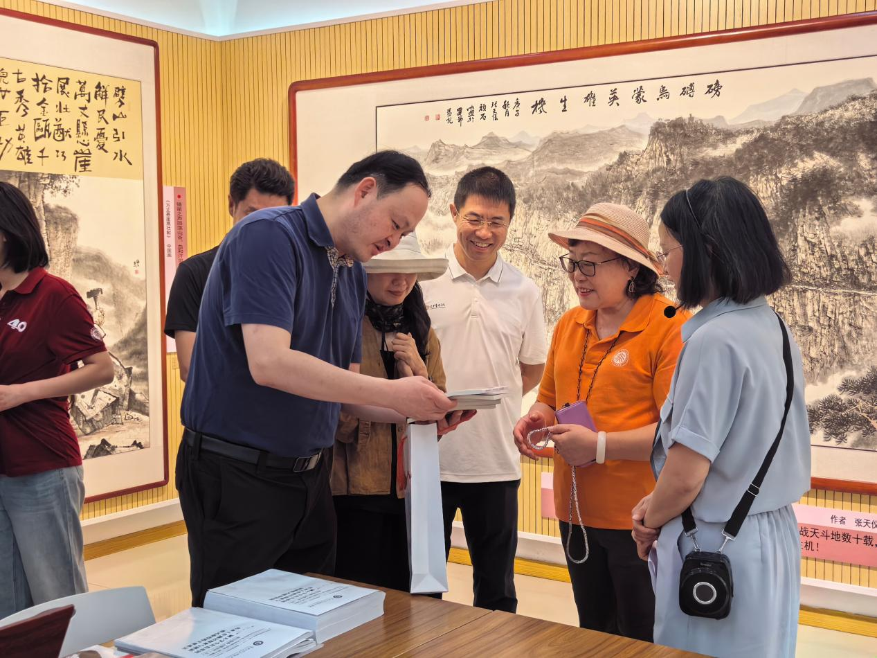 张嗣杰校长向厉放女士赠送红色文化图书。