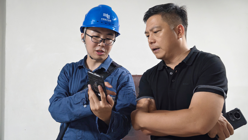 工作人员向酒店负责人讲解暑期用电安全常识。