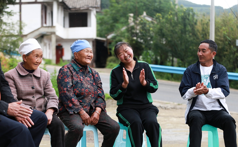 6月17日，王佳美（左二）在威宁自治县双龙镇凉山社区朝阳组与村民一起唱红歌。高琦摄