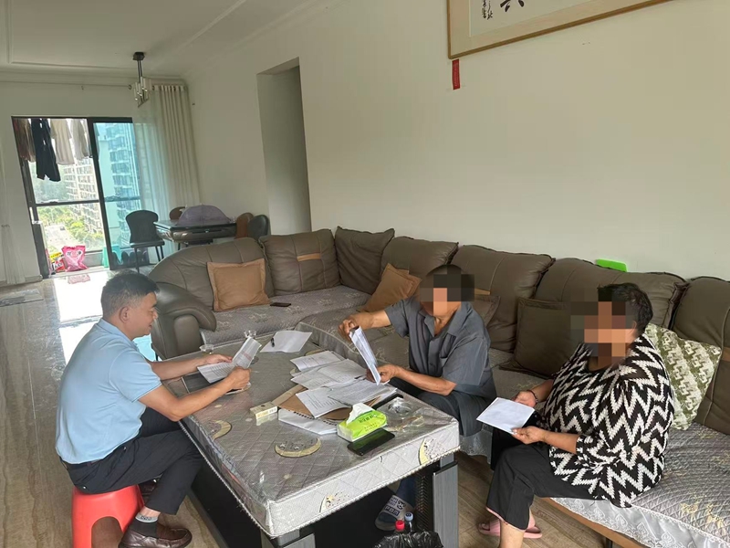 干部到周某家中走訪查閱相關資料。
