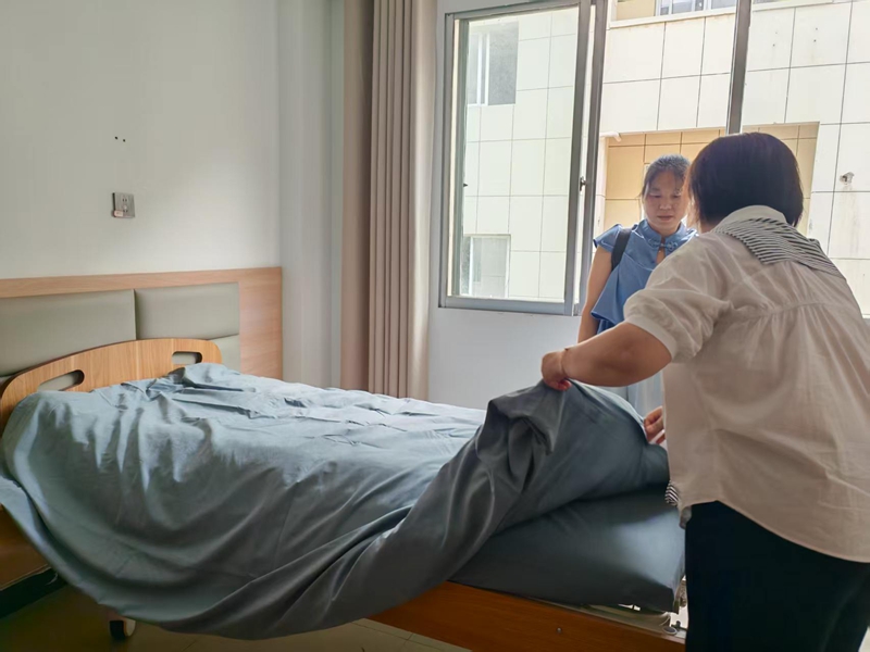 敬老院护工给老人铺床铺.jpg