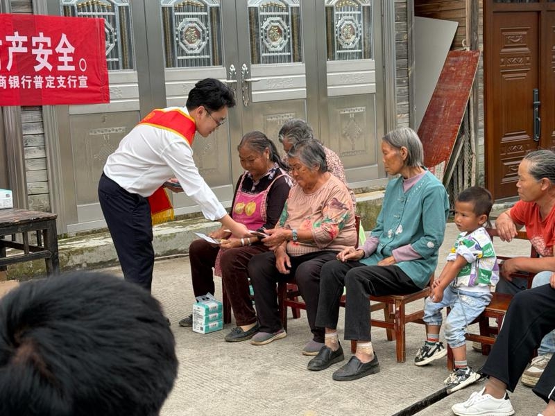 图为该行工作人员正在向农户发放宣传折页，并讲解相关金融知识.jpg