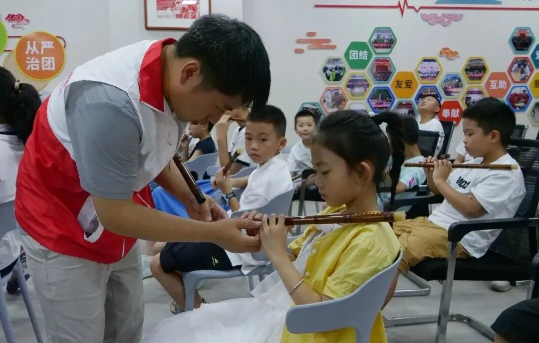 青年志愿者教孩子们学习箫笛。