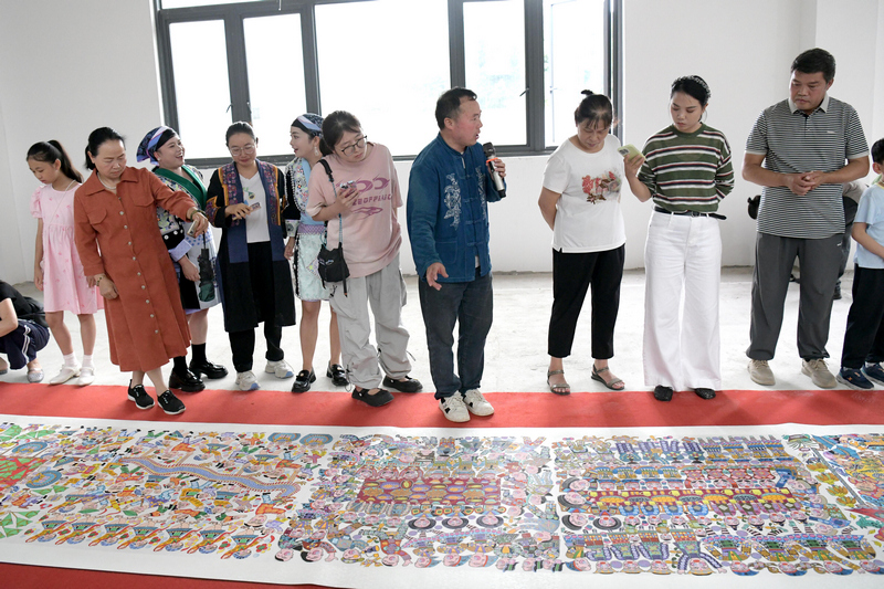 苗族画师兰开军向观众介绍长卷描绘内容。