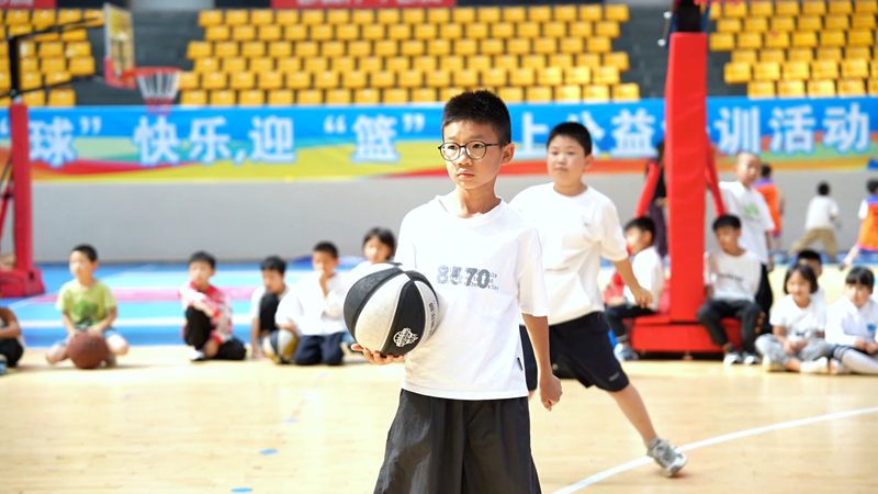 “盘盘小课堂”学员、旅居游客司马睿轩正在听教练讲解篮球知识。