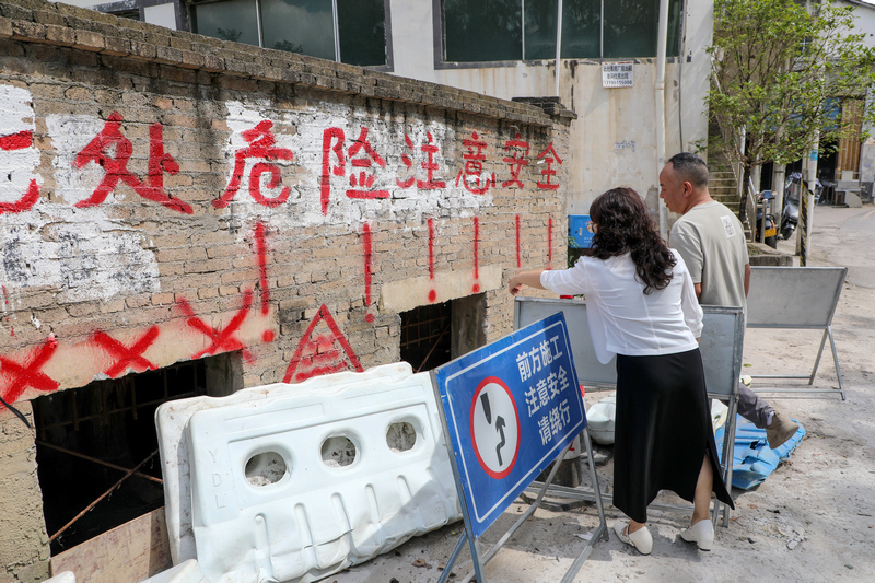 任丽娟向金华镇综治中心工作人员介绍整改后下水道的排污情况。