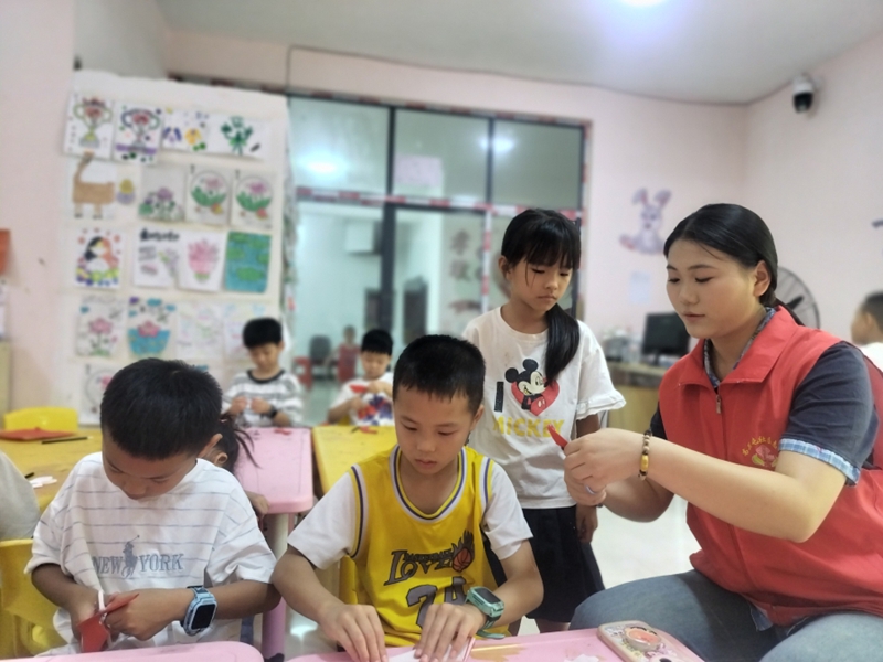 4、㵲水街道高关屯社区暑托班，志愿者正在指导孩子们开展剪纸。（周飞 摄）