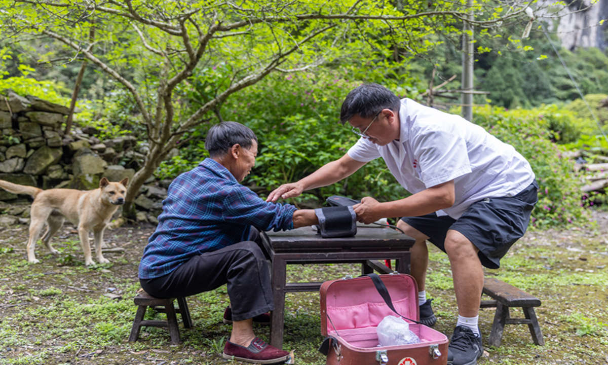2026年8月14日，李崇寬（右）在貴州省黔東南苗族侗族自治州施秉縣白垛鄉白垛村山洞組給村民測量血壓。（磨桂賓 攝）