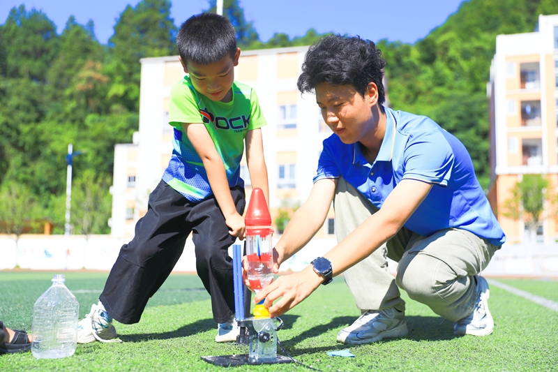 在剑河县城关五小大学生志愿者在指导小朋友发射“水火箭”。杨洁茹摄