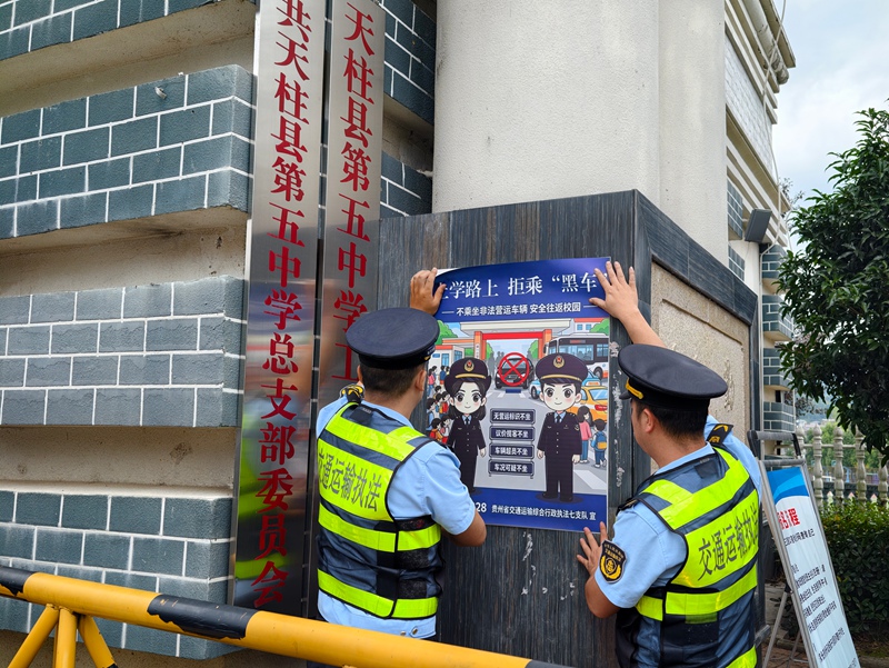 3 执法人员在校园门口张贴宣传海报