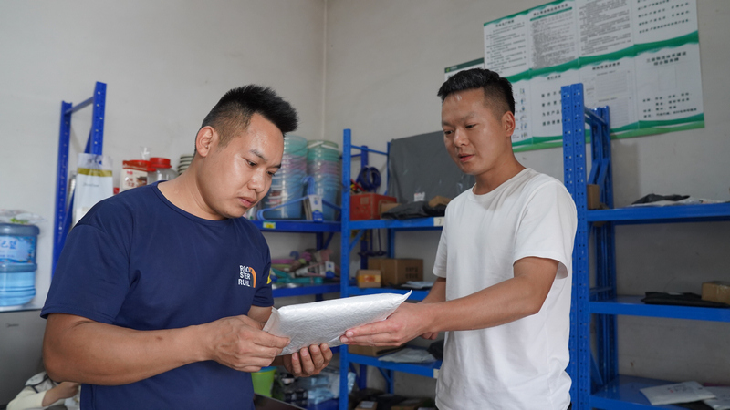 村民馮杰（左）到客貨郵綜合便民服務站領取包裹。