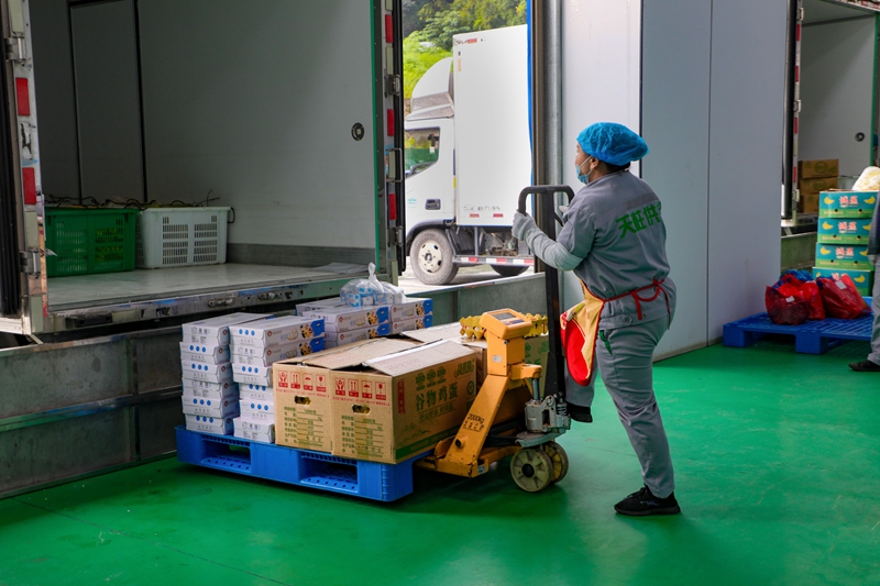 工作人员将打包整齐的各类食品装车。