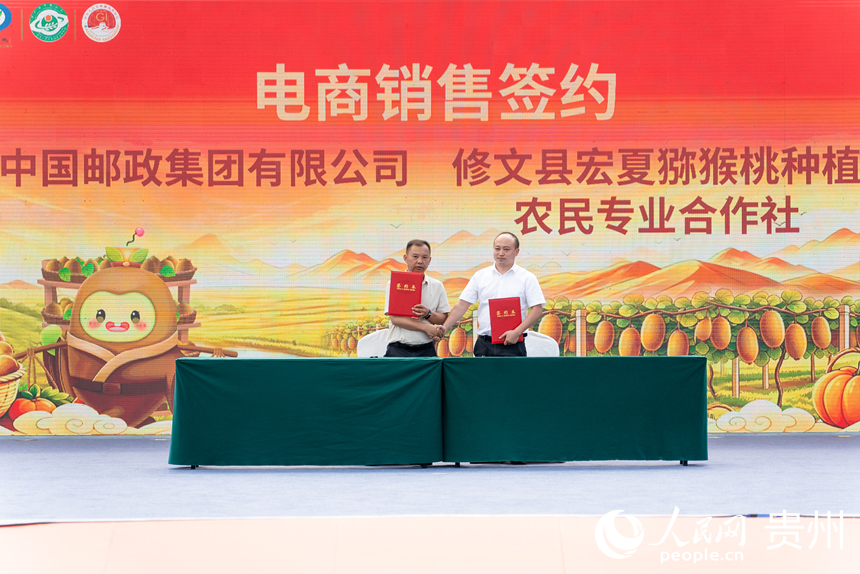 2 活动现场，中国邮政集团有限公司修文县分公司与当地猕猴桃种植农民专业合作社签订合作协议。人民网记者 涂敏摄