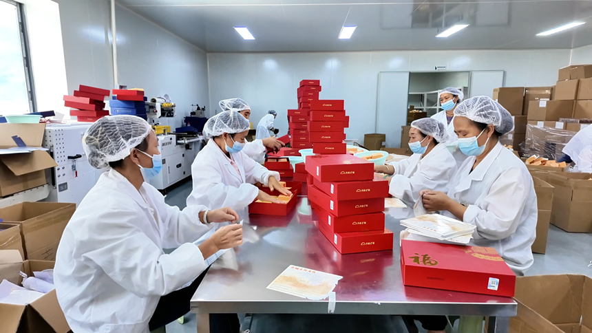 圖為工人們有序地進行月餅禮盒打包、裝箱。