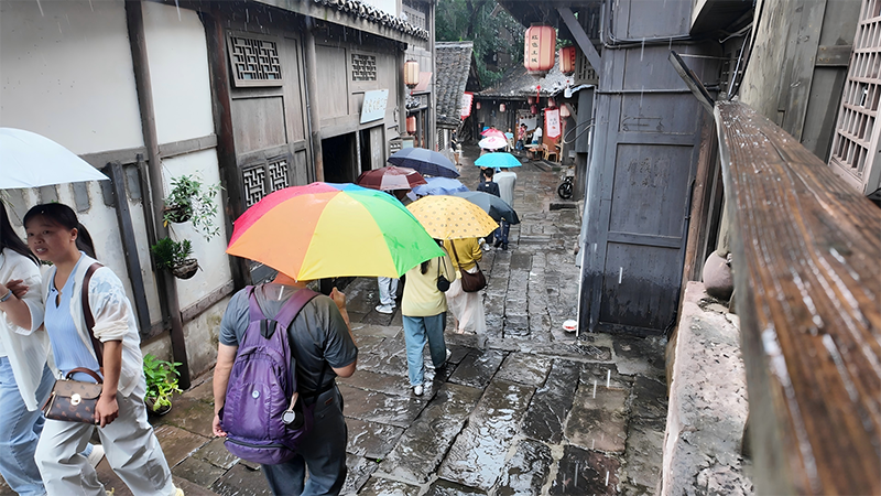 秋雨漫土城，游客撑伞漫步千年古街巷。王烨摄