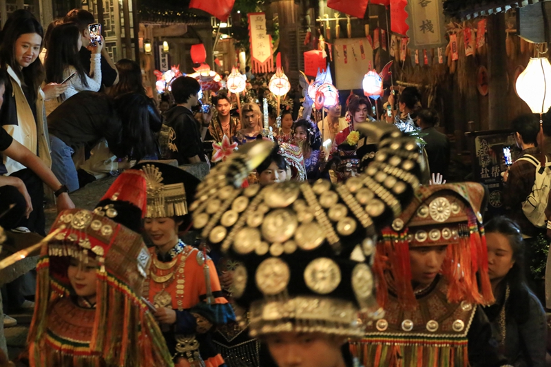 2026年10月2日晚，游客在贵州省遵义市播州区乌江寨景区与艺人参与民俗演艺互动。