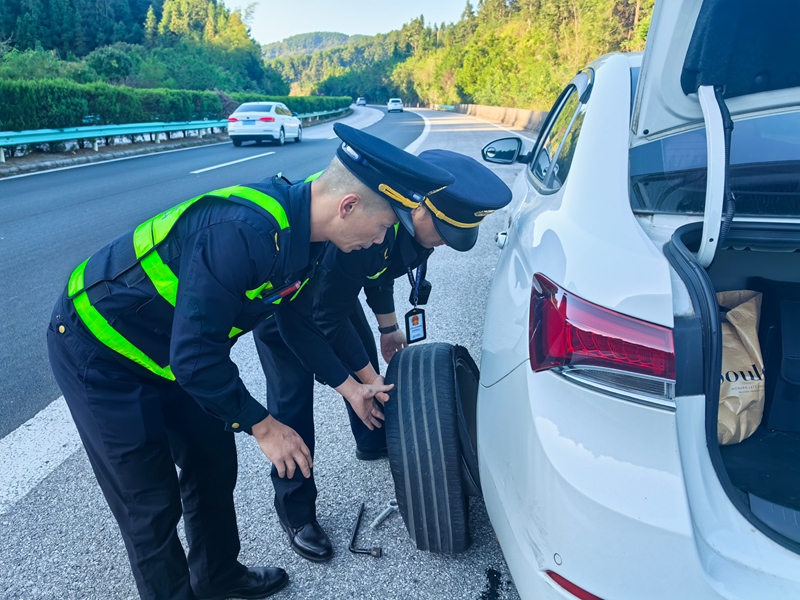2 圖為國慶節期間，貴州交通運輸綜合執法人員幫助駕駛員更換輪胎中。