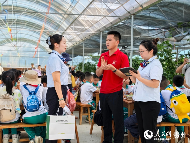 江军海给邮储银行平塘县支行工作人员介绍基地推出的研学体验模式。人民网 李永馨摄