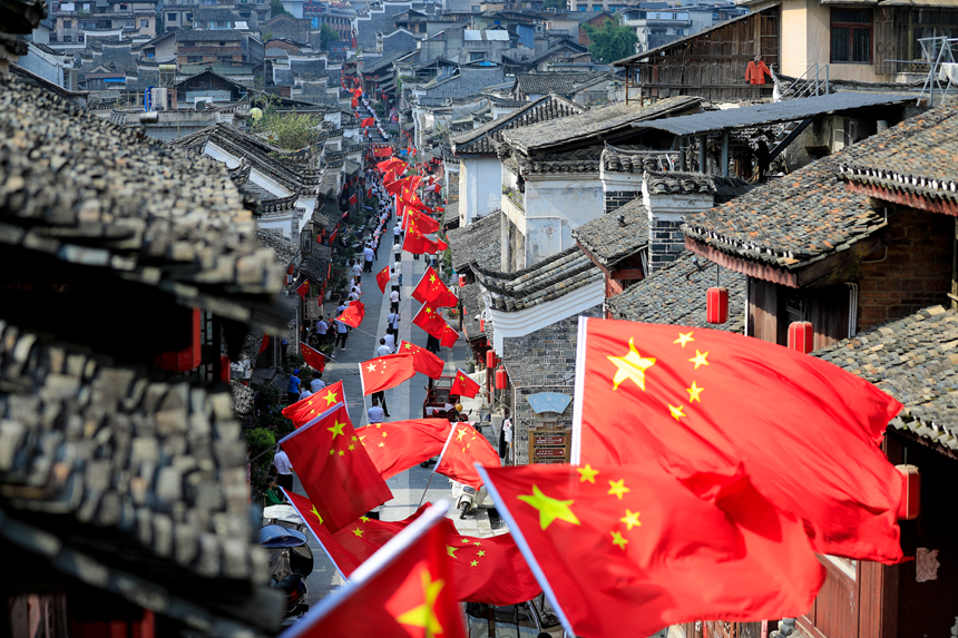 在黎平县古城翘街，旗手挥动国旗喜迎国庆。