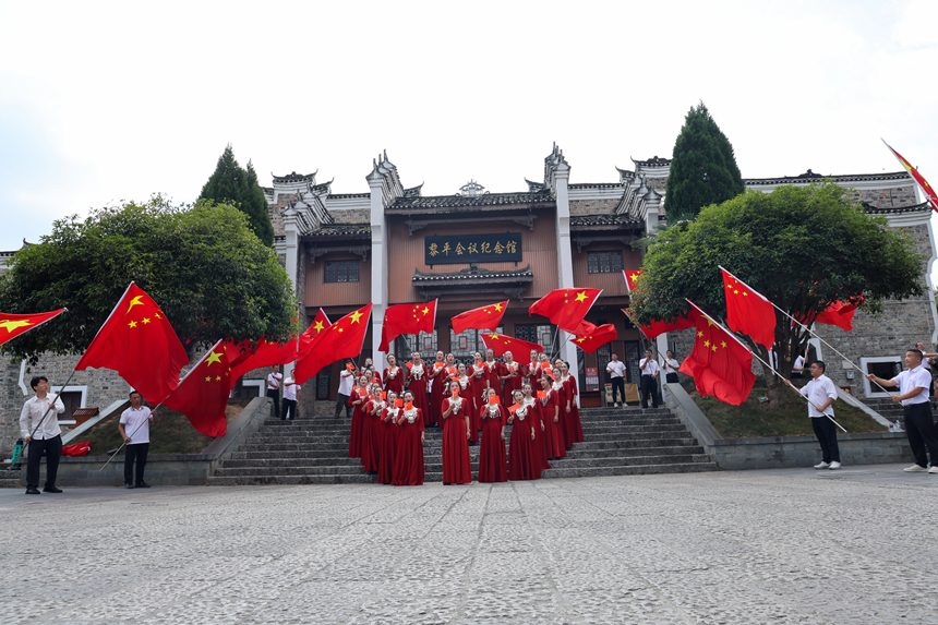 在黎平县会议纪念馆广场，干部群众代表挥动五星红旗，用歌声礼赞祖国，喜迎国庆。