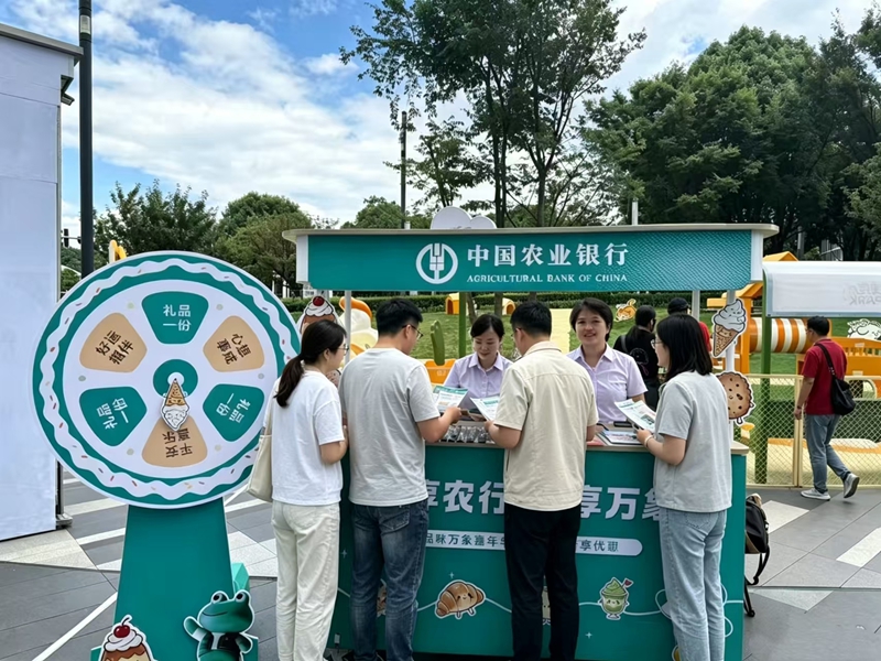 图为农行工作人员为打卡逛市的市民讲解信用卡优惠活动